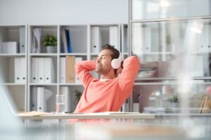 Young relaxed businessman enjoying music in headphones